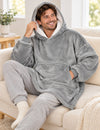 Homme en Pull Plaid Polaire Homme gris installé confortablement sur un canapé dans un salon lumineux