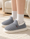 Chaussons Alix gris portés avec des chaussettes blanches, les deux pieds posés sur un tapis