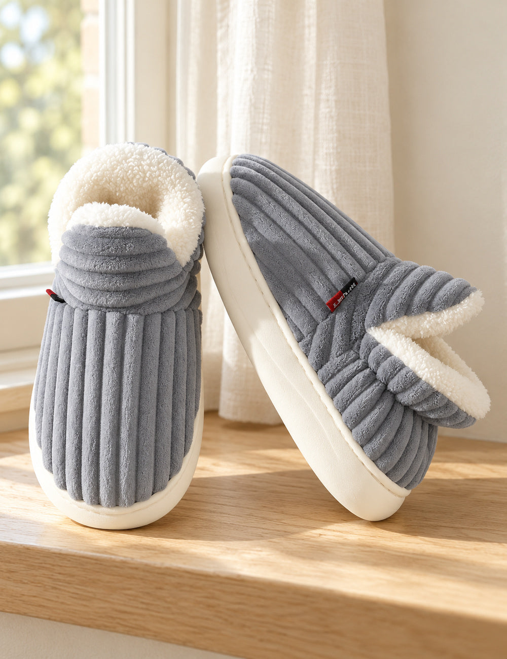 Chaussons Alix gris vus de face et de côté sur un rebord en bois clair