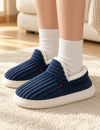 Chaussons Alix bleu marine portés avec des chaussettes blanches, pieds posés sur un tapis