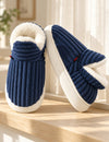 Chaussons Alix bleu marine vus de face et de côté sur un rebord en bois clair