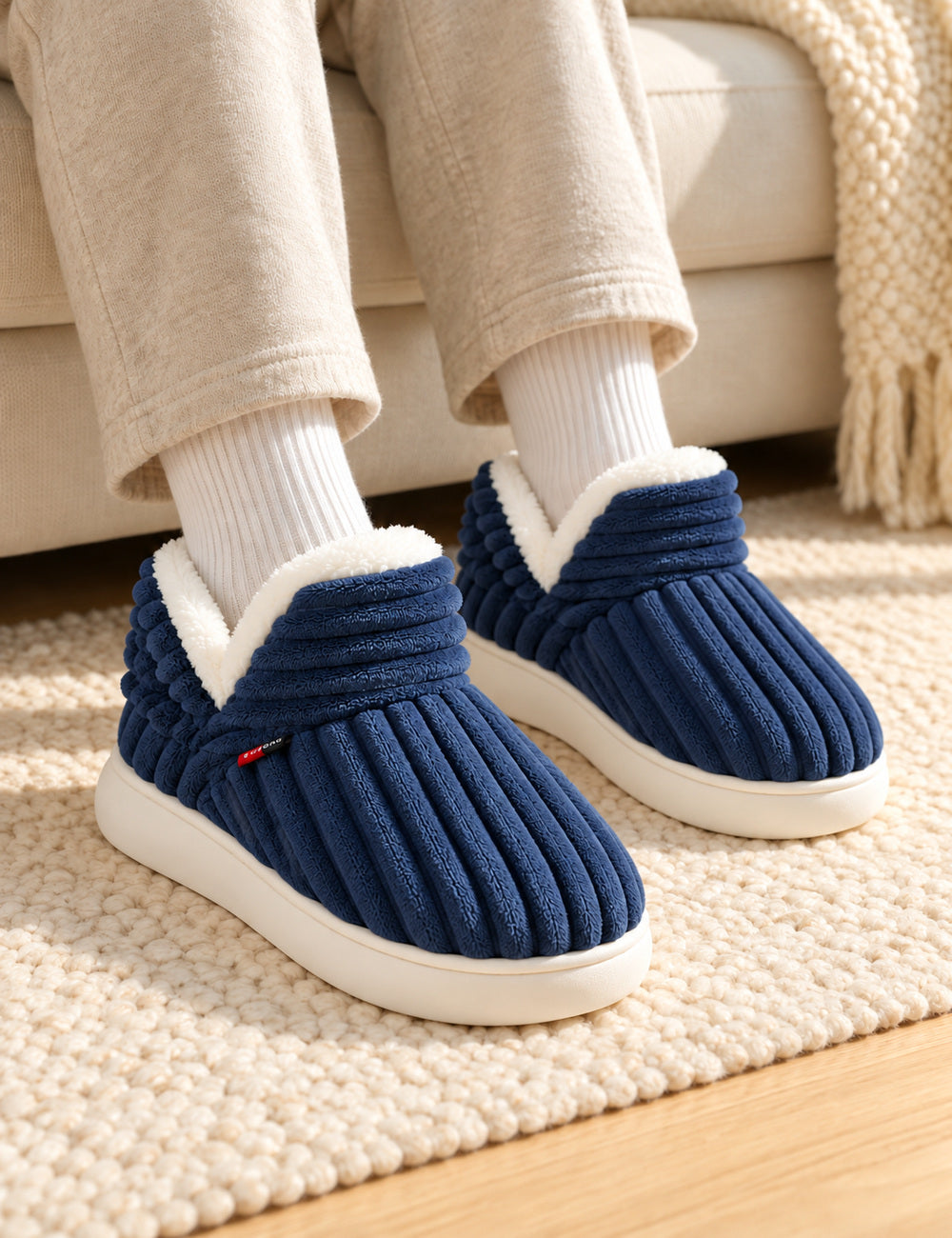 Chaussons Alix bleu marine portés avec des chaussettes blanches, pieds à plat sur un tapis