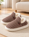 Paire de chaussons Alix marron taupe sur un tapis ivoire, rabat avant relevé et doublure blanche
