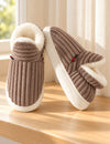Paire de chaussons Alix marron taupe vue de face et de côté sur un rebord en bois
