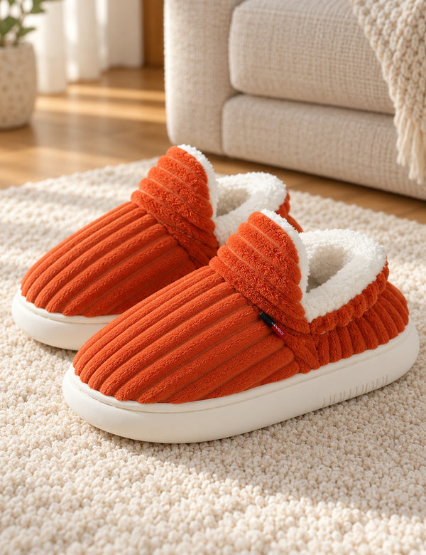 Paire de chaussons Alix orange sur un tapis ivoire, rabat avant relevé et doublure blanche