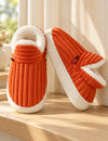 Chaussons Alix orange vus de face et de côté sur un rebord en bois clair